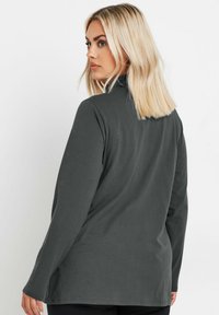 Długa koszula w ciemnoszarym kolorze, wykonana z miękkiej tkaniny z luźnym krojem, z okrągłym dołem i minimalnymi detalami szwów.