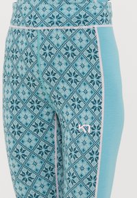 Μπλε κολάν αθλητικών ρούχων με σχέδιο διαμαντιού και λουλουδιών, με λεία υφή και λογότυπο σε ανοιχτό ροζ χρώμα στο πλάι.