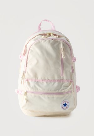 Sac à dos Converse All Star couleur crème avec fermetures éclair roses claires, sangles, plusieurs compartiments et poignée supérieure.