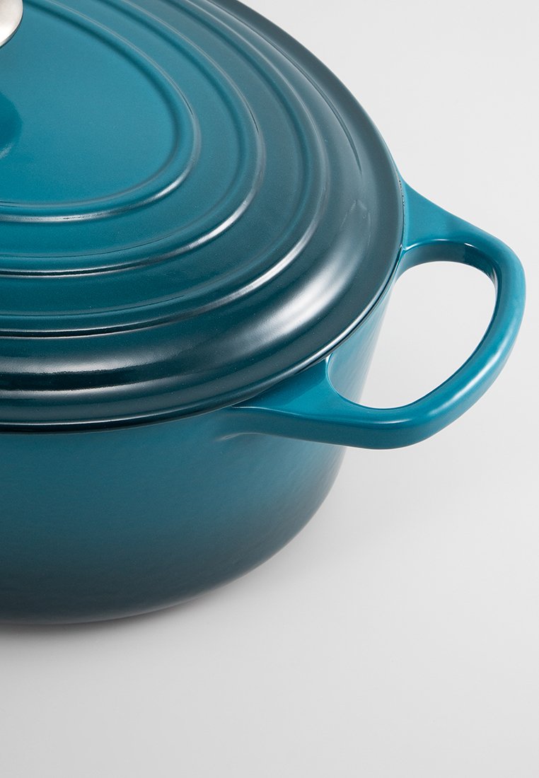 Gietijzeren pan in teal, ronde vorm met een gladde afwerking, een bolle deksel en een stevige handgreep voor gemakkelijk grippen.