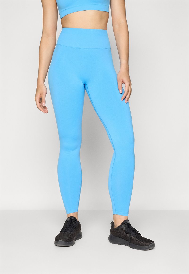 Light blue leggings made of stretchy fabric, featuring a high waistband and a sleek, form-fitting design, paired with black athletic shoes.
