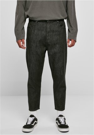 Black denim jeans with a straight leg cut, featuring five pockets, a zip fly, and subtle texture. Worn with black sneakers and white socks.