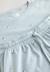 Set de pijamale bleu deschis cu model cu dungi și imprimeu mic de pinguini, talie elastică cu șnur și mâneci scurte. Material de bumbac moale.