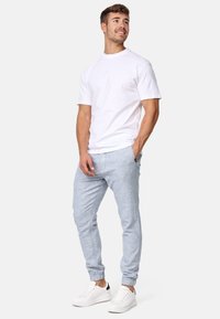 Camiseta blanca de algodón con cuello redondo, combinada con pantalones jogger azul claro con tejido texturizado y puños elásticos. Zapatillas blancas.