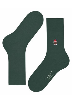 Green socks with a ribbed cuff, featuring an embroidered design of a red hat on a snow-capped chimney; made from soft material.