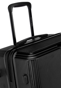 Černý tvrdý kufr s texturovaným povrchem, teleskopickou rukojetí a zipovým uzávěrem. Obsahuje liniový vzor a značkovou rukojeť.