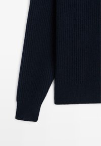 Cuff in maglia a coste navy, realizzato in tessuto testurizzato e con una vestibilità aderente. L'orlo presenta un taglio pulito con un sottile dettaglio a coste.