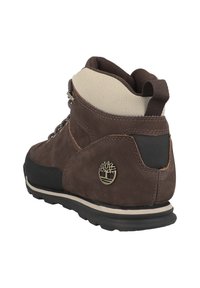 Hnědá kožená turistická bota s polstrovaným límcem, gumovou podrážkou, kovovými očky a logem na patě. Texturovaný a odolný design.