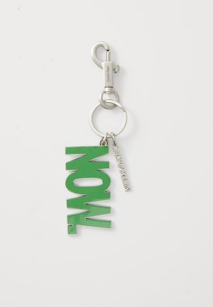 Green acrylic keychain featuring "NOW" in bold lettering, attached to a silver metal split ring and a clasp, with a small branded tag.