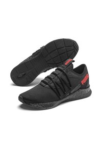 Zapatillas deportivas negras con parte superior de malla texturizada, acentos rojos, suela gruesa y cuello acolchado. Cuenta con un sistema de cordones para un ajuste seguro.