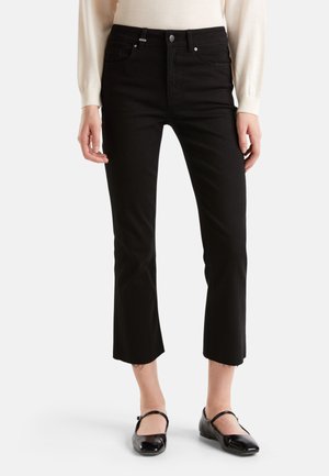 Jean noir court avec taille haute, doté d'une fermeture à bouton et de poches avant. Le matériau a une texture lisse avec un léger effilochage sur les bords de l'ourlet.