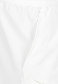 Pantalones cortos de tela blanca que presentan una textura suave, cinturilla elástica y un bolsillo lateral con una cremallera oculta. Diseño sencillo para versatilidad.