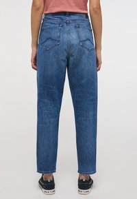 Jeans de mezclilla azul oscuro con cintura alta, pierna recta, textura sutil y dos bolsillos traseros de parche con costura en zigzag.