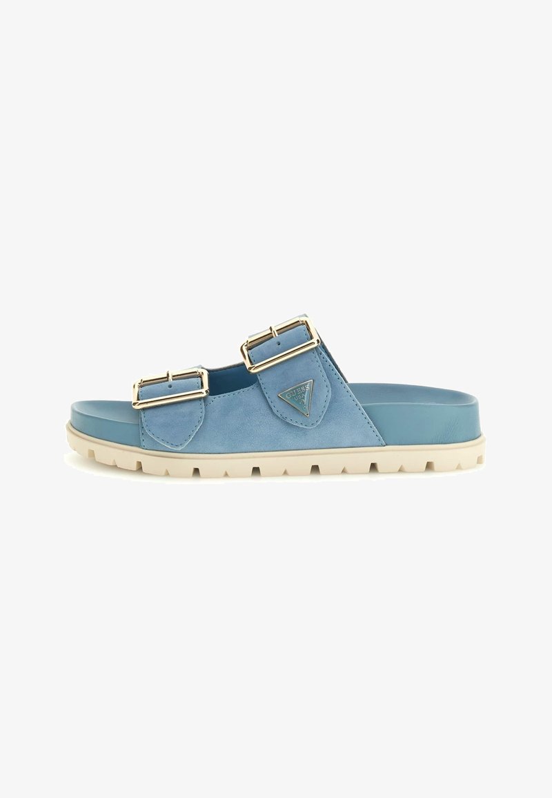 Blaue Wildlederslidesandalen mit zwei metallicfarbenen Schnallen, strukturierten Akzenten und einer kontrastierenden weißen Gummisohle.