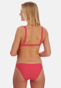 Rosa Bikini-Set mit verstellbaren Trägern und klassischem Schnitt, aus glattem, dehnbarem Stoff und minimalem Metallzubehör auf der Rückseite.