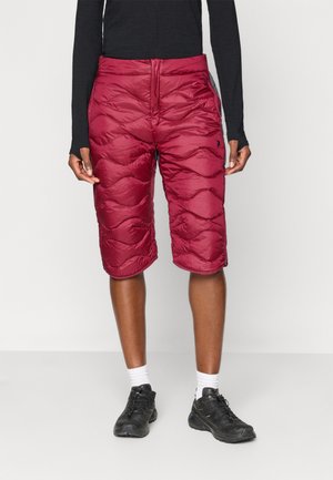 Shorts isolados em Borgonha com um padrão acolchoado, apresentando uma cintura elástica e bolsos laterais, feitos de material sintético leve.