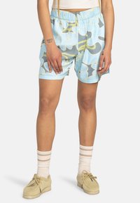 Shorts bleus avec un motif floral jaune et gris, dotés d'une taille élastique et de poches latérales. Tissu texturé et léger.