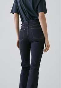 Mörkblå denim jeans med utsvängda ben, fem fickor, synliga sömmar och en figurnära midja. Mjuk textur med klassisk design.