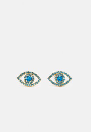 Pendientes de botón de tono dorado con forma de ojos abiertos, con piedras azules que delinean el ojo y una piedra azul más grande en el centro.