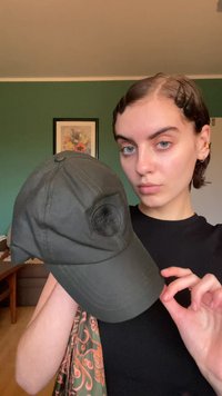 Olive green baseball cap with a rounded crown, stiff brim, and a circular fabric patch on the front. Made of durable material.