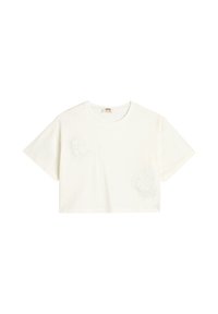 Camiseta corta blanca de algodón, con dos diseños de corazones texturizados de encaje en la parte delantera. Mangas cortas y cuello redondo.