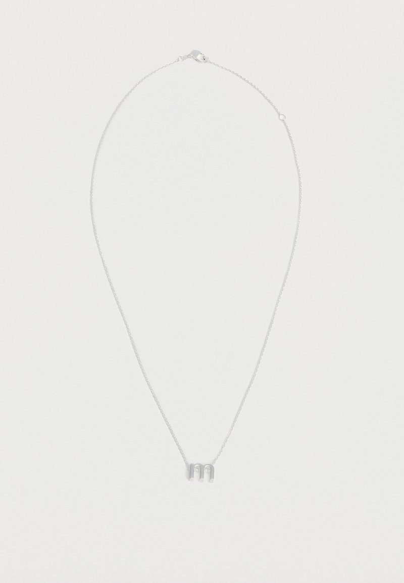 Collier chaîne en argent avec pendentif petite lettre minuscule "m" centré sur un fond blanc uni.