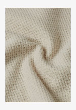 Beige wafelkatoen stof met zachte plooien en een gestructureerd ruitpatroon.