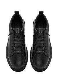 Zwarte leren sneakers met een gladde afwerking, voorzien van een gewatteerde textuur aan de voorkant, elastische veters en een trekriem op de hiel.