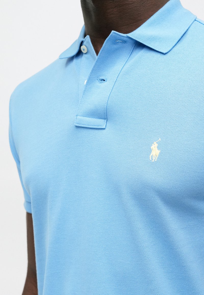 Lichtblauw polo shirt van geweven katoen, met een drieknoopsluiting en een klein wit logo op de linkerborst.