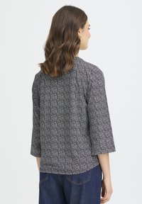 Marineblå bluse med blomsterprint, trekvartlange ærmer og rund halsudskæring, lavet af letvægtsstof, der giver en afslappet pasform.