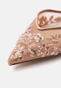 Terav alatooniline king, millel on läbipaistev kangas ning kaunistatud keeruka lillemustriga litrite ja helmestega.