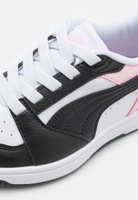 Schwarz-weiße Sneakers mit pinken Akzenten; ausgestattet mit einem strukturierten Leder-Obermaterial, weißen Schnürsenkeln und perforierten Details auf der Zehenbox.