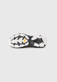 Semelle de baskets noire avec un profil en caoutchouc blanc, dotée de crampons multidirectionnels pour une meilleure adhérence et d'une surface texturée pour une traction optimale.