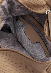 Beige perforerad läderväska med ett gråmönstrat foder, utrustad med en dragkedjeficka och en varumärkesetikett präglad på en läderlapp.