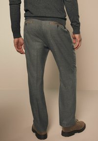 Grau karierte Hose mit taillierter Passform, ausgestattet mit einer glatten Textur, zwei Gesäßtaschen und braunen Stoffakzenten an der Taille.
