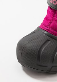 Botas de textil fucsia con suela de goma negra texturizada, que cuentan con una puntera redondeada y un patrón de relieve prominente para mayor adherencia.