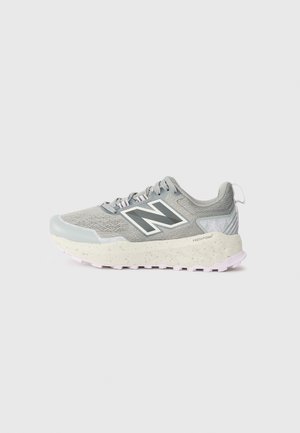 Szaro-biały but sportowy New Balance z cholewką z siateczki, grubą nakrapianą podeszwą i dużym logo "N" po prawej stronie.