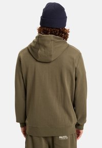 Olivengrøn hoodie lavet af blødt stof, med en rummelig hætte og ribbede manchetter. Vist fra ryggen med et mærket accent ved kanten.