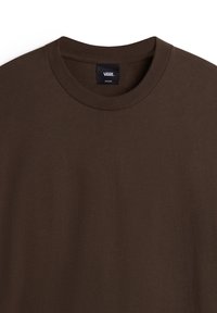 Braunes Baumwoll-T-Shirt mit Rundhalsausschnitt und kurzen Ärmeln. Enthält ein „VANS“-Label im Kragen. Glatte, einfarbige Textur.
