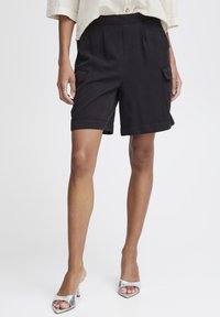 Shorts cargo noirs avec deux poches latérales, coupe ajustée, longueur genou, fabriqués en tissu léger, avec des ourlets repliés et une texture lisse.
