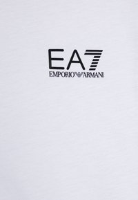 Hvit bomulls T-skjorte med svart trykk av "EA7" og "EMPORIO ARMANI" logo. Myk tekstur med rund hals.
