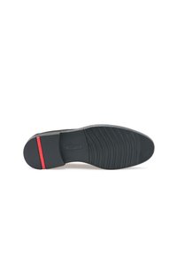 Semelle en caoutchouc noir à texture nervurée, avec un accent rouge et un détail logo. Design plat adapté à divers styles de chaussures.