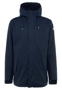 Marineblå vandtæt jakke med høj krave, justerbar hætte, to sidelommer og for i faux fur. Har snoretræk og elastiske manchetter.