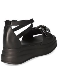 Svarta lädersandaler med kilklack som har en tjock, strukturerad sula och korsade remmar med en metallisk detalj på ovansidan.