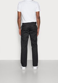 Czarne spodnie o prostym kroju, wykonane z tkaniny wytwarzanej w splocie. Posiadają szlufki na pasek, tylne kieszenie oraz kontrastowe szwy. Połączone z białymi trampkami.