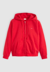 Veste à zip rouge en matériau polaire doux. Comprend une capuche avec cordon, des poches avant et un petit logo sur la partie gauche de la poitrine.