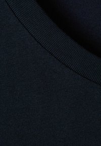 Țesătură de bumbac de culoare albastru închis, cu un decolteu rotund cu fasii, evidențiind o textură fină și o suprafață netedă. Design minimalist, fără modele.