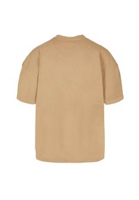Béžové oversized tričko s krátkým rukávem vyrobené z jemné látky, s kulatým výstřihem a zaobleným spodním lemem. Žádné viditelné vzory ani doplňky.