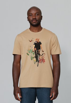 Beige katoenen t-shirt met een grafisch ontwerp van een fietser met een tijgerkop, omringd door kleurrijke bloemen en planten, korte mouwen, standaard pasvorm.