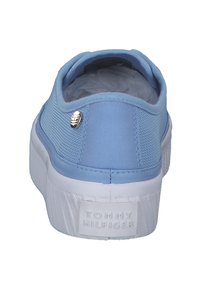 Scarpa slip-on blu in tela con una parte superiore texturizzata, suola in gomma bianca e un logo argentato sul retro.
